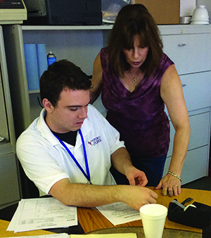 Forum student working with Ramsey staff at a desk 