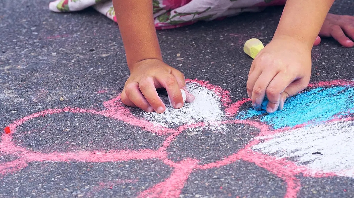 Child drawing on sidewalk with colored chalk