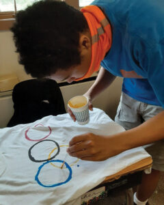 Forum School male student painting the Olympic Rings